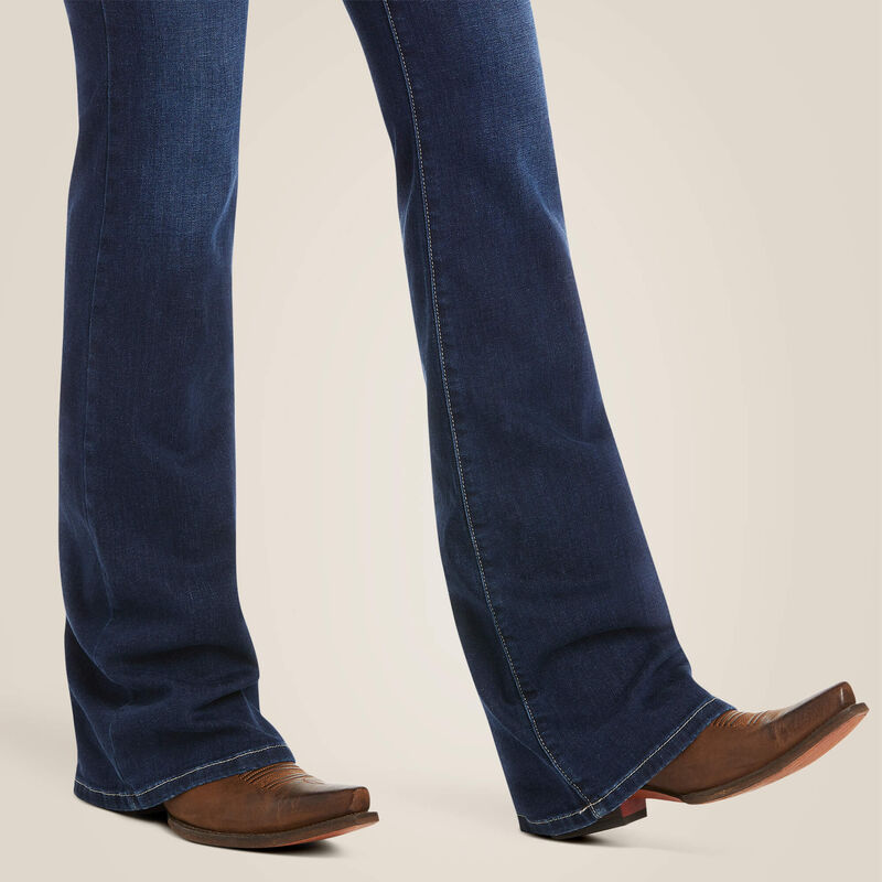 Blue jeans worn with brown cowboy boots on a beige background