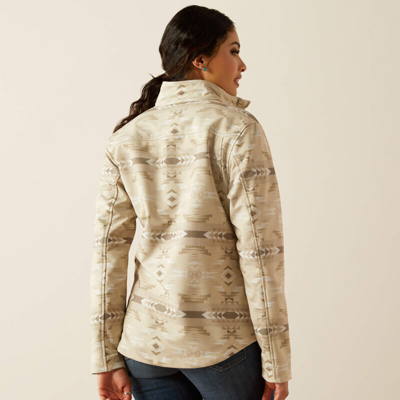 Woman wearing a beige patterned jacket on a plain background