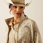 Woman wearing a beige patterned shirt and cowboy hat on a beige background