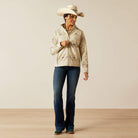 Woman wearing a beige jacket, blue jeans, and a cowboy hat on a plain background