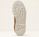 The outsole of a brown shoe, showing a textured white tread pattern and the embossed ARIAT brand logo, photographed against a light beige background.