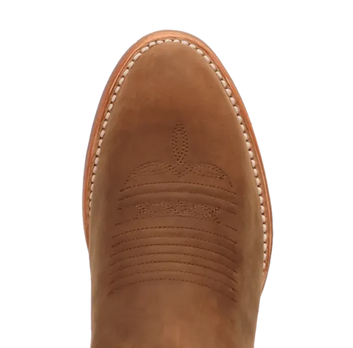 A close-up of a tan suede boot toe showing decorative stitching and a debossed logo, set against a dark blue background with a Dan Post logo in the corner.