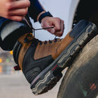 Person changing a tire with a focus on their boots.