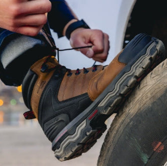 Person changing a tire with a focus on their boots.